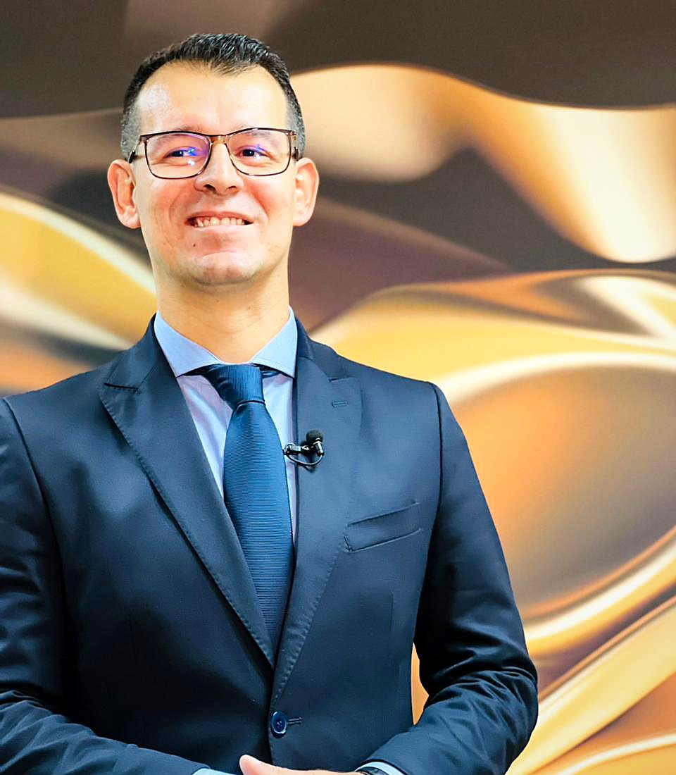 Dr. Wesley Silva Correia, advogado, de terno azul-marinho, diante de um painel dourado
